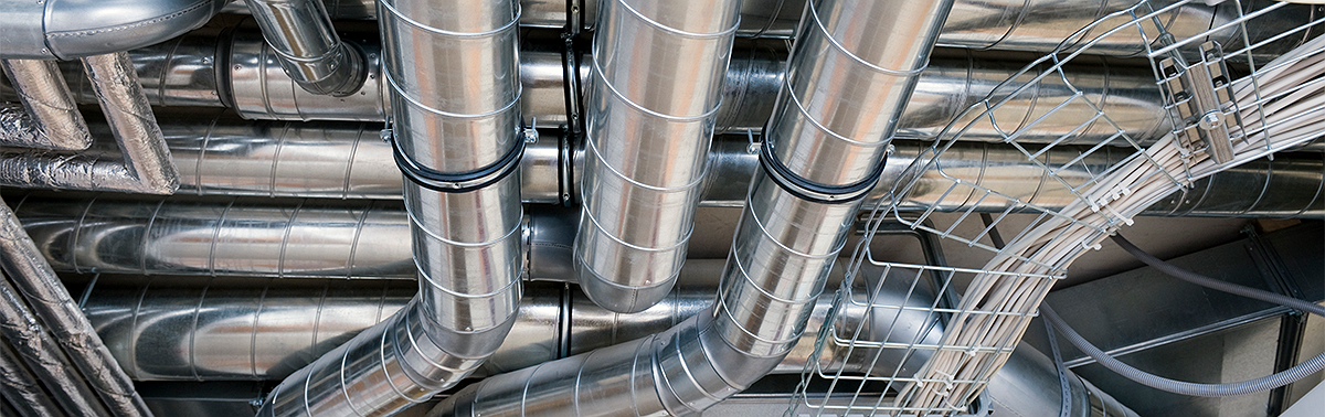 Close-up of metal pipes and conduits in a construction or industrial setting, showcasing plumbing infrastructure.